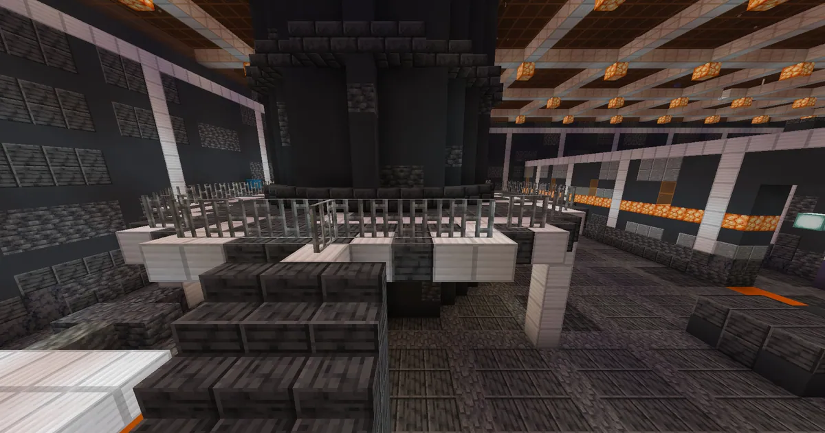 A furnace tower ringed by a railed catwalk in a dark foundry hall, orange lamps hanging from the roof.